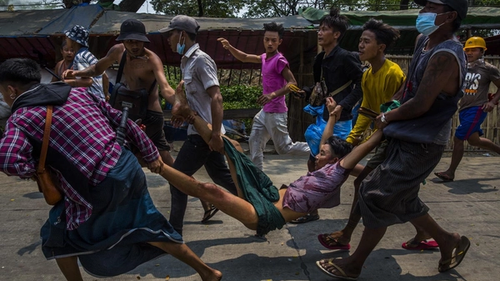 Протестующие уносят раненого во время разгона демонстрации в Янгоне, 2021