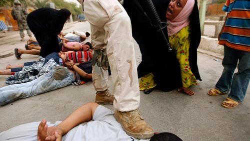 Иракская женщина реагирует на то, как американские и иракские солдаты выводят мужчин из дома и задерживают их во время совместной военной операции в районе Садр-Сити в Багдаде, 12 июля 2008 года.